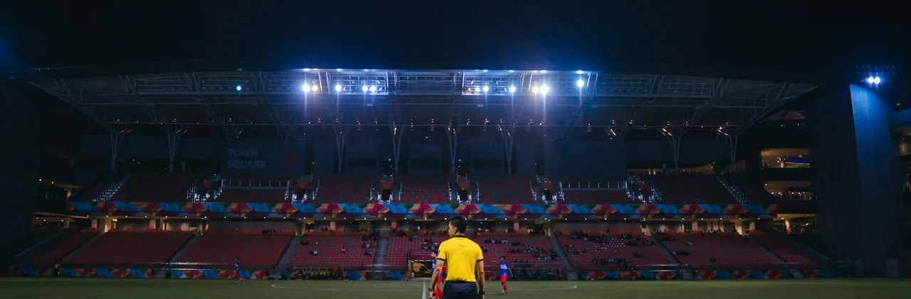 Una figura solitaria en una cancha iluminada por focos de estadio de noche